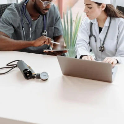 Medical Professionals Looking at the Screen of the Tablet while Sitting Next to Each Other